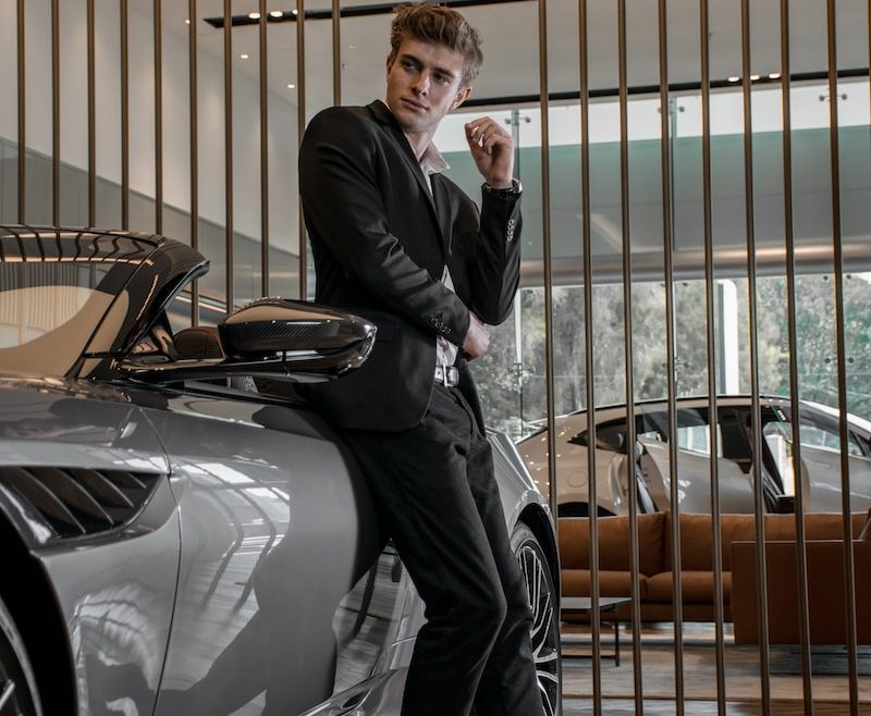 man in black suit standing beside silver car