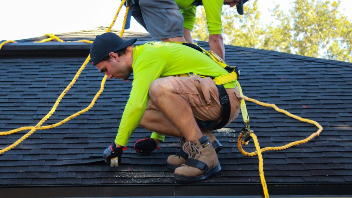 two men working on the roof of a house