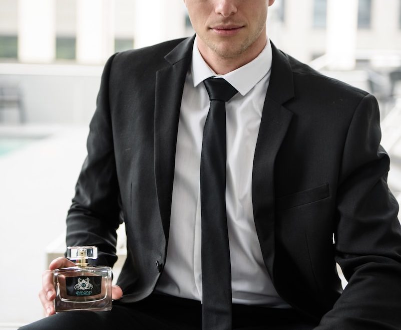 man in black suit holding brown ceramic mug